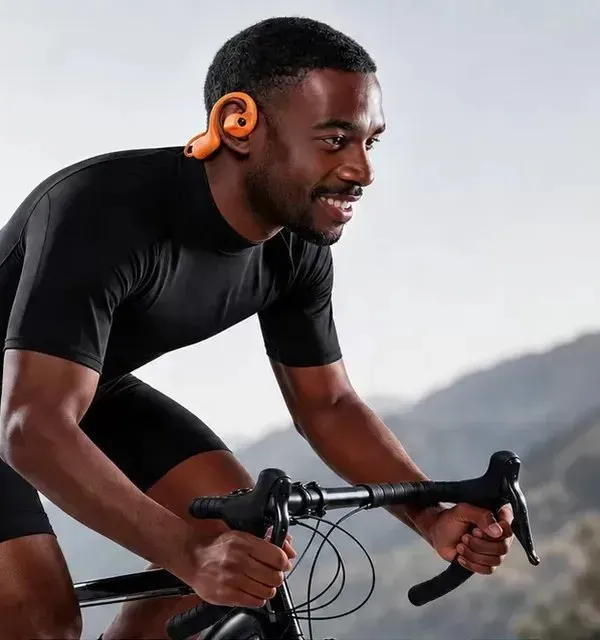 Ciclista con audífonos de oído abierto en la montaña